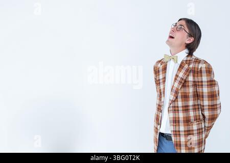 Ein Mann, der hinten im Studio die Hände einschließt, trägt Blazer und Fliege, Kopierraum Stockfoto