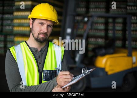 Mann mittleren Alters, der Lagerbestand mit Klemmbrett und Schutzweste inspiziert, Kopierraum Stockfoto