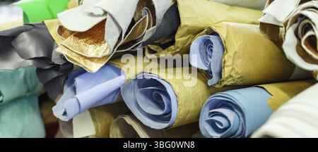 Stoffrollen, umwickelt in Bastelpapier, die aufeinander liegen. Herstellung. Nahaufnahme Stockfoto