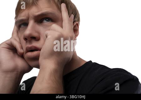 Besorgter junger Mann mit blonden Haaren in einem schwarzen T-Shirt denkt über Probleme nach und hält den Kopf Stockfoto