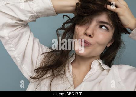 Nahaufnahme Porträt der positiven attraktiven verrückt fröhlich lustig junge lockige Brünette Frau auf blauem Hintergrund isoliert Stockfoto