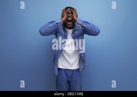 Schockierter afrikanischer Mann mit Dreadlocks in Jeansjacke gewann die Lotterie Stockfoto
