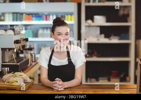 Weibliche Barista steht hinter der Theke im Café und bereitet Sandwiches an der Espressomaschine zu Stockfoto