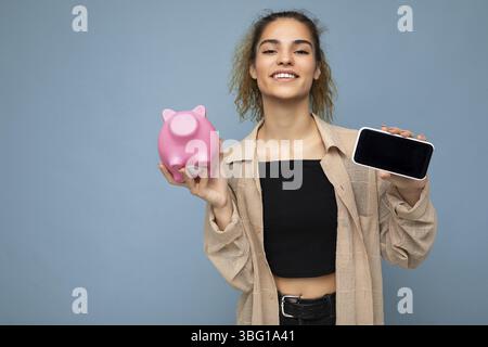 Portrait Foto von glücklich positiv lächelnd junge schöne attraktive Brünette lockig Frau mit aufrichtigen Emotionen tragen stilvolle beige Hemd isoliert ov Stockfoto