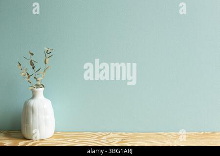 Vase aus Eukalyptusblättern auf Holztisch mit grünem Hintergrund Stockfoto