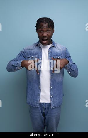 Vertikales Porträt eines hübschen jungen, stilvollen afrikanischen Mannes mit Locken in Denim-Kleidung Stockfoto
