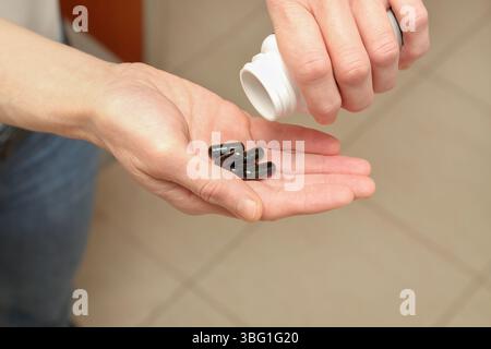 Eine Frau, die eine Reihe von Pillen in ihre Palmennaht gießt Stockfoto