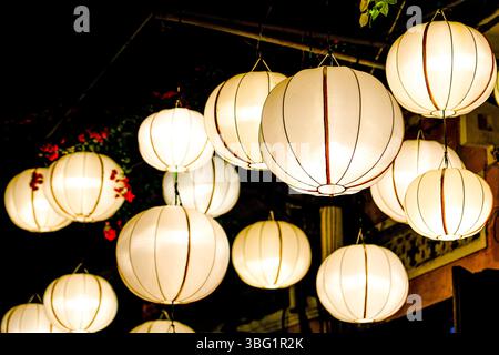 Leuchtende traditionelle weiße Laternen hängen nachts und beleuchten die Straße mit warmem, sanftem Licht Stockfoto