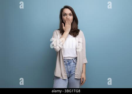 Hübsche europäische brünette junge Frau in einem stilvollen Look auf blauem Hintergrund mit Kopierraum Stockfoto