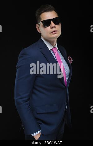 Junger kaukasischer eleganter, intelligenter und freundlicher Geschäftsmann ernsthaft nachdenklicher Mann in blauem Anzug, der im Büro steht Stockfoto