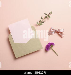 Kraft-Umschlag und leere Karte mit Statikblüte, Eukalyptusblätter auf pinkfarbenem Hintergrund. Blumendesign, flacher Lay, Draufsicht, Kopierbereich Stockfoto