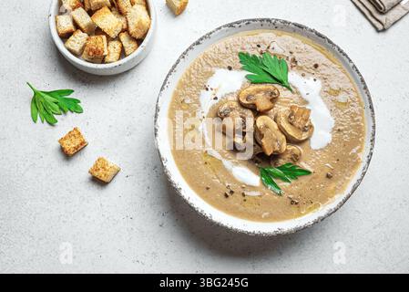 Pilzcremesuppe in Schüssel garniert mit Croutons und Kräutern, Draufsicht, Kopierraum. Champignon-Pilzsuppe im Herbst. Stockfoto