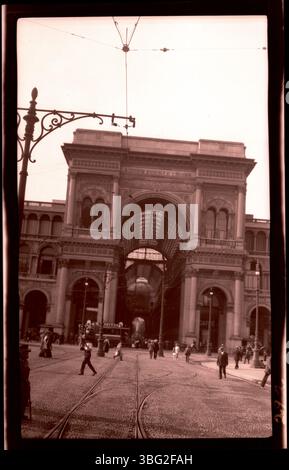 1913 Foto der Galleria Vittorio Emanuele II in Mailand, Italien. Das Bild zeigt Straßenbahnen, die am Eingang des Einkaufszentrums aus den 1860er Jahren vorbeifahren, eines der ältesten und berühmtesten Gebäude Italiens. Das Foto wurde während der Europatour der Arrases aufgenommen und bietet einen historischen Blick auf dieses Wahrzeichen von Mailand. Stockfoto