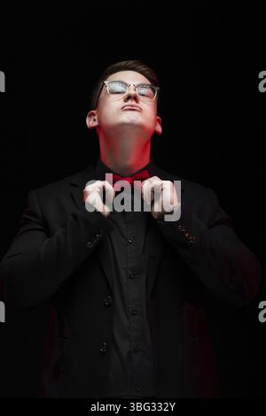 Junge kaukasier Elegante schwere Smart erfolgreiche Mann im schwarzen Anzug mit Bow-tie-in Büro weg schauen lächelnd zur Festsetzung Bow-tie Stockfoto