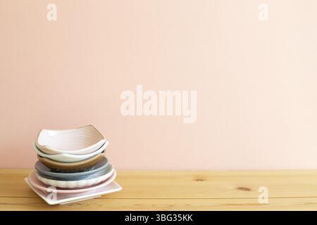 Stapel von bunten Geschirr auf Holztisch. Rosa Hintergrund Stockfoto