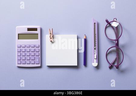 Notizblock, Buntstift, Cutter, Taschenrechner, Brille auf violettem Hintergrund. Arbeitsbereich. Flach liegend, Draufsicht Stockfoto
