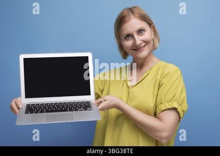 Freudige Geschäftsreife Frau, die Laptoptechnik für den Fernberuf beherrscht Stockfoto