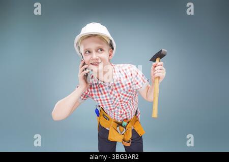 Junger Baumeister mit Baubandmaß in der Hand und Schutzhelm, der am Handy spricht Stockfoto