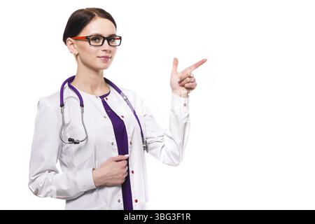 Porträt einer jungen attraktiven lächelnden Ärztin, die im Büro steht und in der Kamera in weißer Uniform mit leerem Bereich blickt Stockfoto