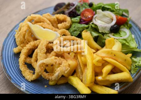 Gebratene Tintenfischringe mit Pommes frites und Salat Stockfoto