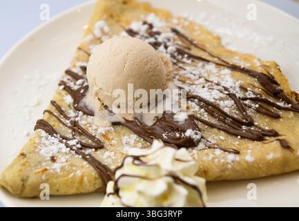 Pfannkuchen mit Eis und Schokoladensauce auf einem weißen Teller Stockfoto