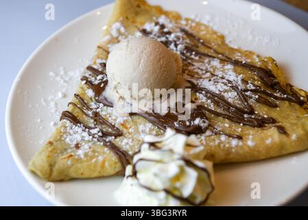 Pfannkuchen mit Eis und Schokoladensauce auf einem weißen Teller Stockfoto