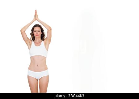 MittelErwachsene Frau, die Yoga-Gebetspose im Studio mit Sportbekleidung hält, Kopierraum Stockfoto