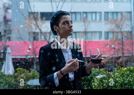 Eine junge Frau mit Weinglas steht draußen im Schnee Stockfoto