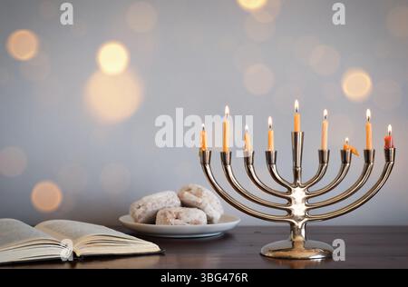 Chanukah Menorah mit Jelly Donuts und torah Buch Stockfoto