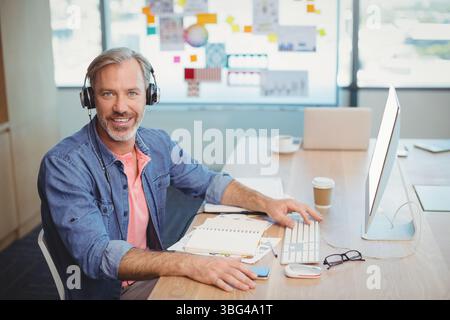 Mitte der 50er Jahre Mann mit Kopfhörern, der am Schreibtisch im Büro sitzt und auf dem Monitor sitzt Stockfoto