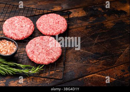 Rohe Fleischpasteten, Schnitzel, Hackfleisch für Burger. Hölzerner Hintergrund. Draufsicht. Stockfoto