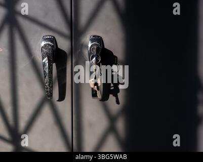 Dieses Bild zeigt schlanke Türgriffe, die dramatische Schatten erzeugen. In der Nähe hängt ein Schlüsselanhänger, der Sicherheit und Zugang in einer modernen Umgebung betont. Stockfoto