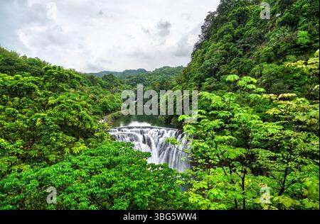Der Shifen Wasserfall im Pingxi District in New Taipei, Taiwan, stürzt sich in einen türkisfarbenen Pool inmitten von dichtem Grün und bietet eine malerische und ruhige natürliche Attraktion, die oft als Little Niagara von Taiwan bezeichnet wird Stockfoto