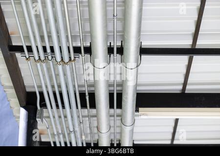 Metallrohrleitung an der Decke. Kabelkanäle Elektrisches Stromleitungssystem, Metallpipeline an der Gebäudedecke installiert. Stockfoto