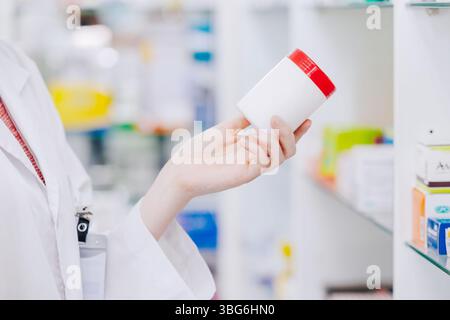 Schließen Sie den Arzt Apotheker Hand hält Medizin Pillen Box aus dem Drogenregal im Drogeriemarkt, um Details auf dem seitlichen Etikett zu sehen Stockfoto