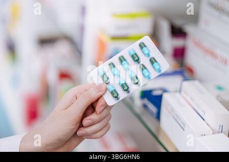 Schließen Sie oben Arzt Apotheker oder Druggist Hand halten Medizin Kapsel Art Pillen Pack mit Drogen Regal in Drogeriemarkt Stockfoto