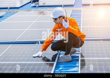 Arbeiter, der Solarpaneele auf dem Dach des Industriegebäudes installiert, große Solarenergiesysteme für eine umweltfreundliche Ökostromversorgung Stockfoto