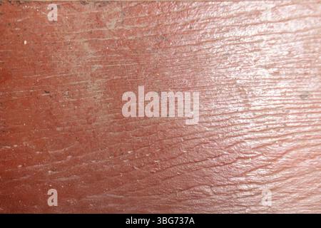 Diese Nahaufnahme zeigt die komplizierte Textur und Maserung einer verwitterten roten Holzoberfläche und unterstreicht die rustikale Schönheit und den natürlichen Charme. Stockfoto