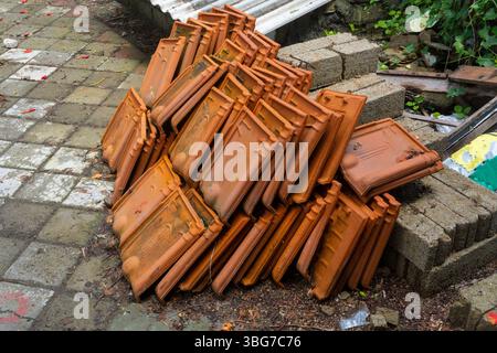 Ein Haufen alter, verrosteter Dachziegel. Die Kacheln sind übereinander gestapelt und haben verschiedene Größen. Konzept von Verfall und Verlassenheit, wie die Fliesen ha Stockfoto