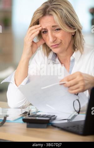 Müde aufgebrachte, reife Geschäftsfrau, die an starken Kopfschmerzen leidet Stockfoto