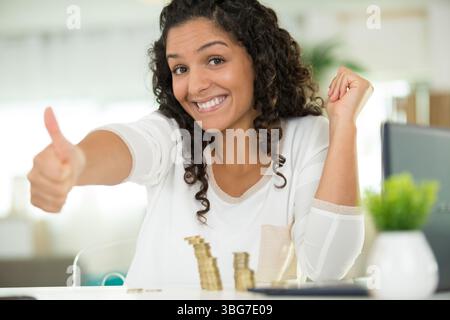 Lady macht Daumen hoch, nachdem sie ihre Ersparnisse gezählt hat Stockfoto