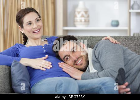 Der Mann lehnte sich auf seinen schwangeren Bauch Stockfoto