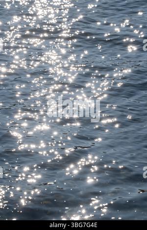 Sonnenlicht reflektiert und funkelt auf einer blauen Wasseroberfläche Stockfoto