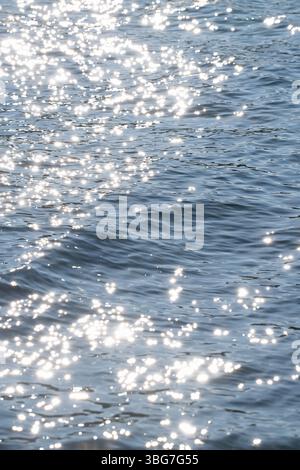 Sonnenlicht reflektiert und glitzert auf einer sich sanft bewegenden Wasseroberfläche Stockfoto