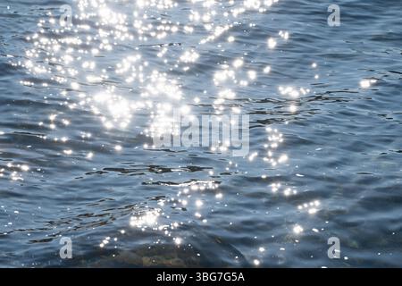 Sonnenlicht erzeugt funkelnde Reflexionen auf der Oberfläche des sanft plätschernden Wassers Stockfoto