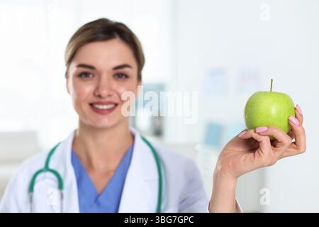 Ernährungswissenschaftler mit grünem Apfel und Stethoskop in der Klinik, selektiver Fokus Stockfoto