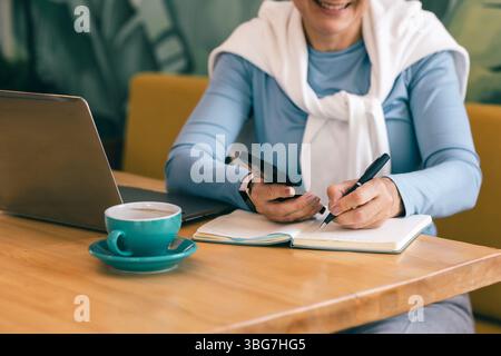 Die Reife Frau der Fernarbeiterin Multitasking in einem gemütlichen Café Stockfoto