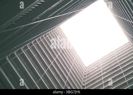 Einzigartiger Blick nach oben auf öffentliche Wohngebäude in Hongkong mit moderner Architektur und lichtdurchfluteten Räumen in einer lebhaften städtischen Umgebung. Stockfoto