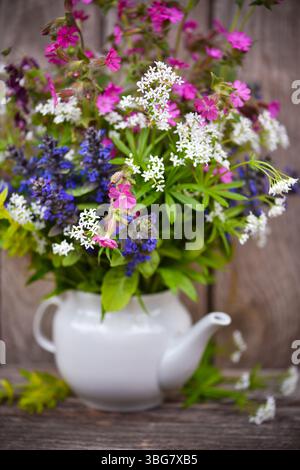 Blumenstrauß aus bunten Wildblumen auf einem alten hölzernen Hintergrund. Stillleben mit wilden Blumen. Selektiver Fokus Stockfoto