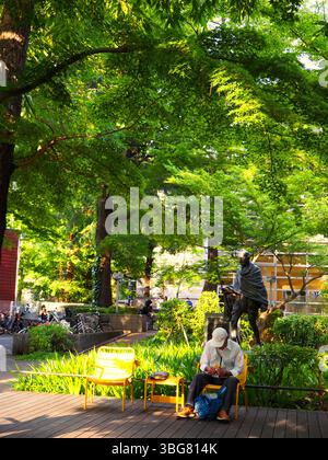 Tokio Park mit Gandhi Statue und Mann, der unter Sommerbäumen sitzt Stockfoto